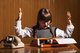 A young girl with hands thrown up, acting frustrated, in front of a desk with 1970's style phone and typewriter, with hands thrown up [Image by creator djoronimo from AdobeStock]